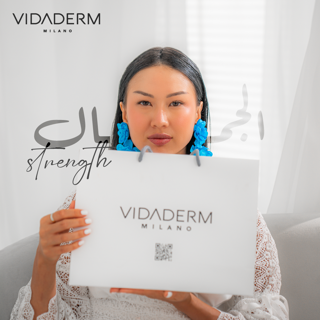 Woman holding a VIDADERM Milano shopping bag with 'Strength' text on a white background